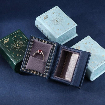 blue, green and sky blue book-style jewelry boxes with a ring 