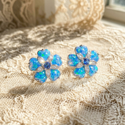 Blue flower-shaped earrings on a textured beige fabric background