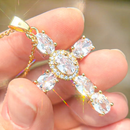 crystal cross necklace with clear white gemstones held between fingers 