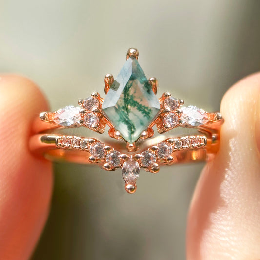 Rose gold moss agate ring held between fingers