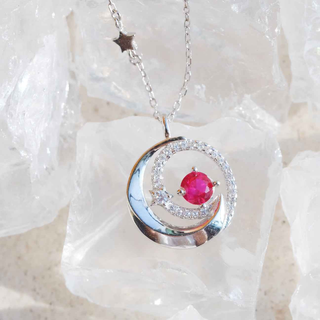STAR WISH moon and star red zircon necklace shown in hand photo